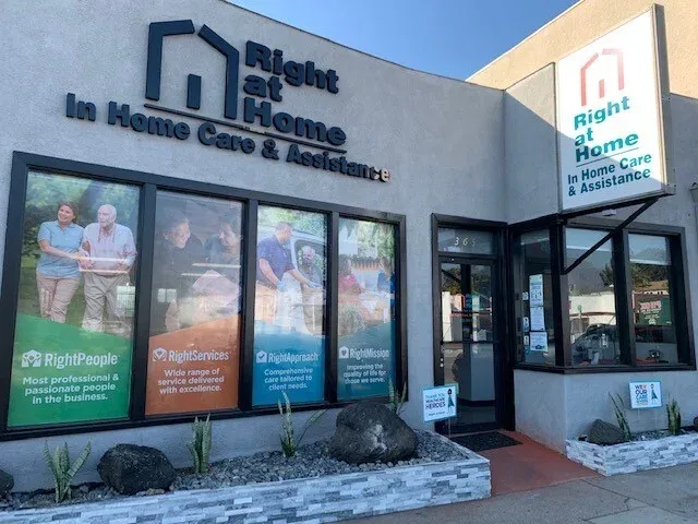 Exterior view of the Right at Home In Home Care & Assistance building, with service descriptions displayed on the sign and windows.